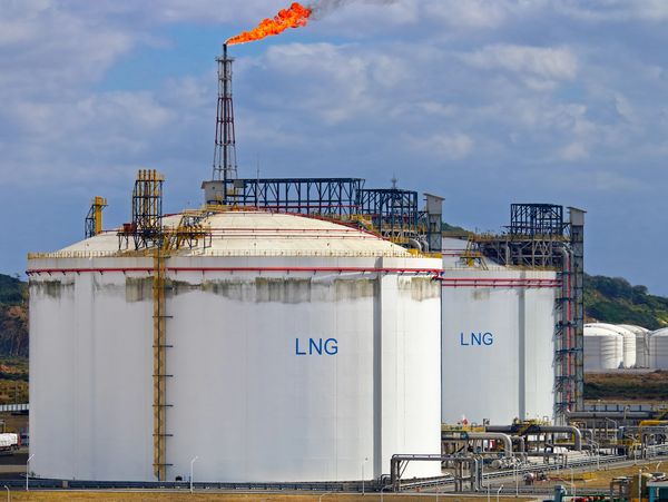 LNG storage tanks beneath a burning gas flare
